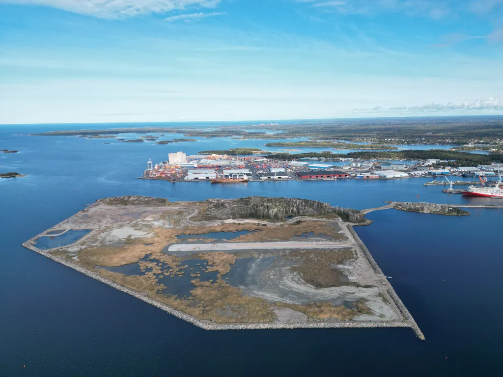 Iso Järviluotoa on laajennettu muun muassa meriväylän ruoppausmassoilla ja viereisen meriteollisuuspuiston louhintamurskeella. Nykyinen pengertie yhdistää Järviluodot telakka-alueeseen. Kuvan oikeassa laidassa, telakan laiturissa, on TT-Linelle rakennettava matkustaja-autolautta. Iso Järviluodon keskellä kulkee uusi pengertie, joka tulee jatkumaan suoraan lahden yli telakka-alueen eteläpuolelle. Näin liikenne siirtyy kauemmaksi lintujen pesistä. Kuvan ylälaidassa näkyy Rauman satamaa. Ensimmäinen epolttoaineen tuotantolaitos sijoittuisi Iso Järviluodon luoteiskulmaan, josta puut on jo aiemmin kaadettu.